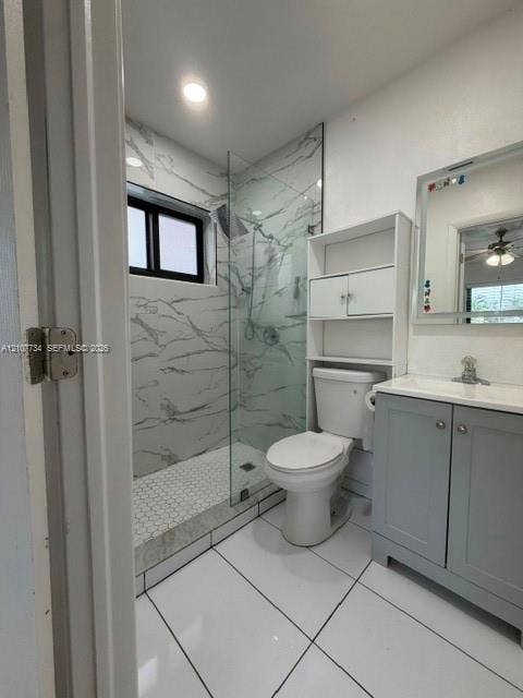 Walk-in shower with stone-finish wall tile, hexagon floor tile, glass enclosure, grey cabinetry, and white tile flooring