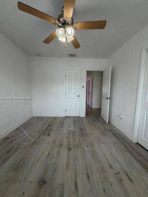 Wood-finish flooring, ceiling fan with integrated lighting, and multi-panel interior doors