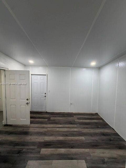 Interior room featuring wood-finish flooring, recessed lighting, and white paneled walls, with two six-panel entry doors