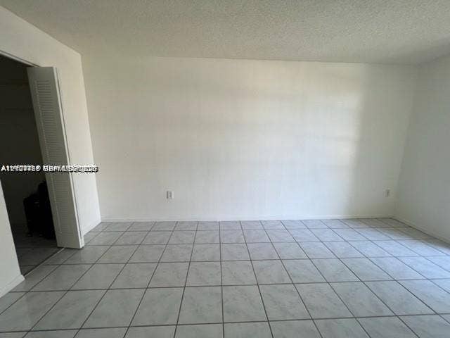 Neutral interior space featuring large-format ceramic tile flooring and a bi-fold closet door