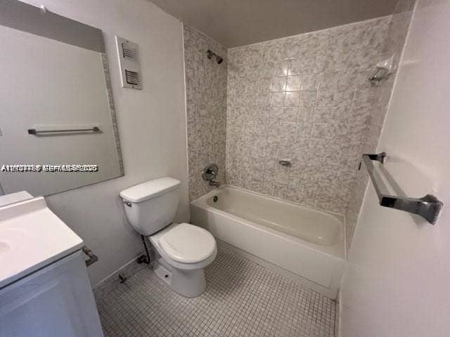 Bathroom featuring a vanity with integrated sink, porcelain bathtub, metallic finish fixtures, wall-mounted mirror, and tiled flooring