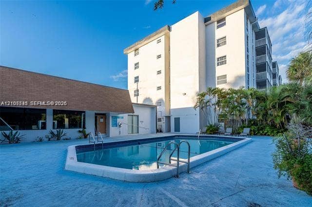 Swimming pool featuring a concrete deck and stainless steel handrails