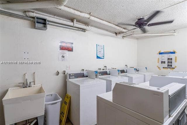 Laundry facility featuring multiple top-load washing machines, a ceiling fan, and a deep basin utility sink