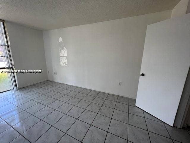 Room featuring large-format ceramic tile flooring and floor-to-ceiling glass sliding doors