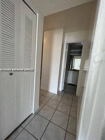 Neutral-toned ceramic tile flooring, floor-to-ceiling closet with louvered double doors, and white interior doors