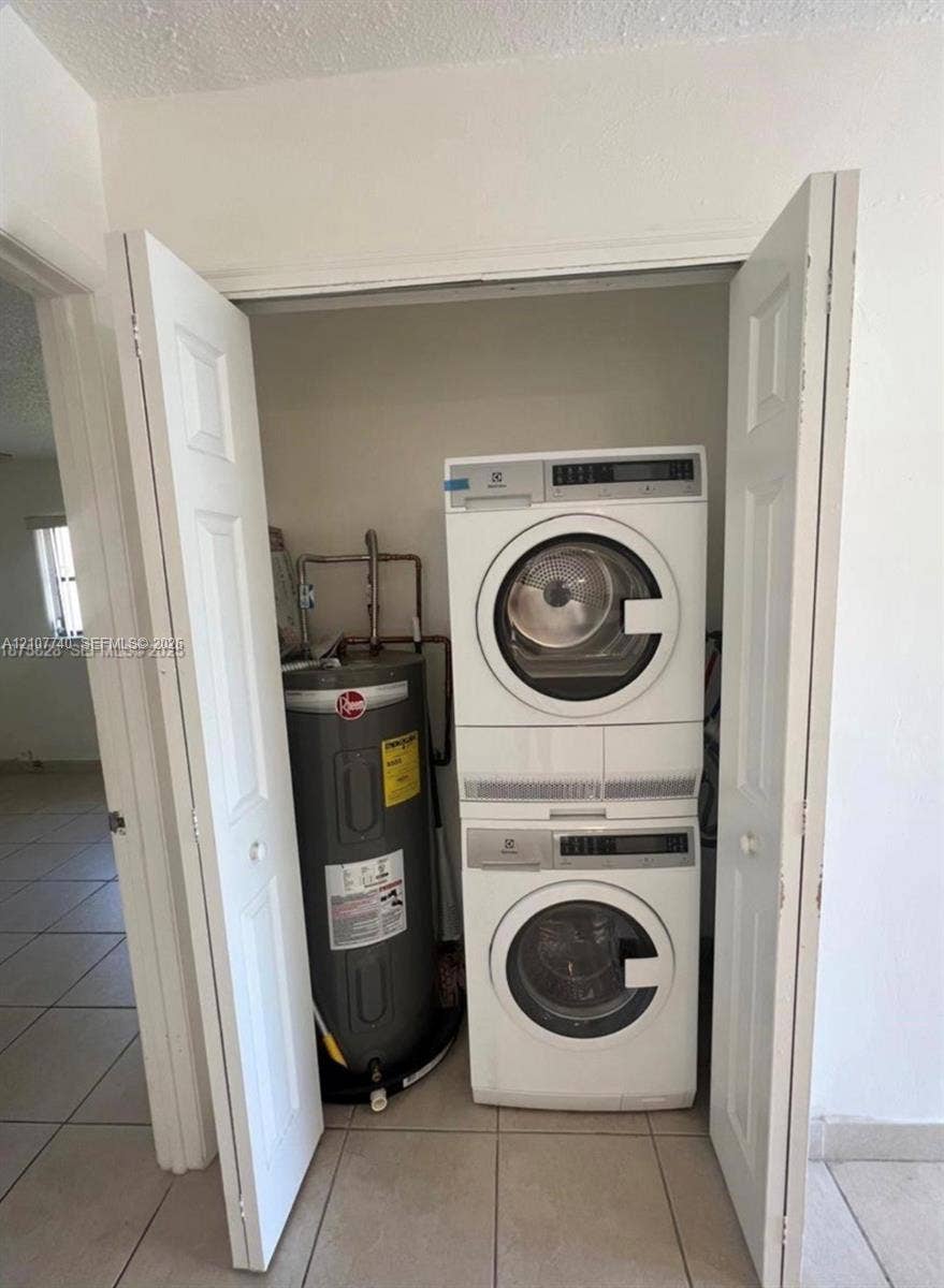 Utility closet featuring a stacked front-loading washer and dryer unit and a vertical water heater