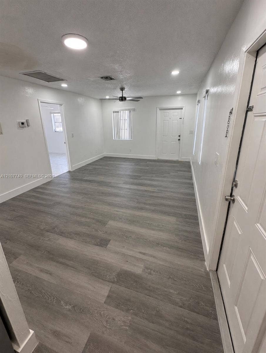 Open interior space featuring wood-finish flooring, recessed lighting, ceiling fan with light kit, and multi-panel doors