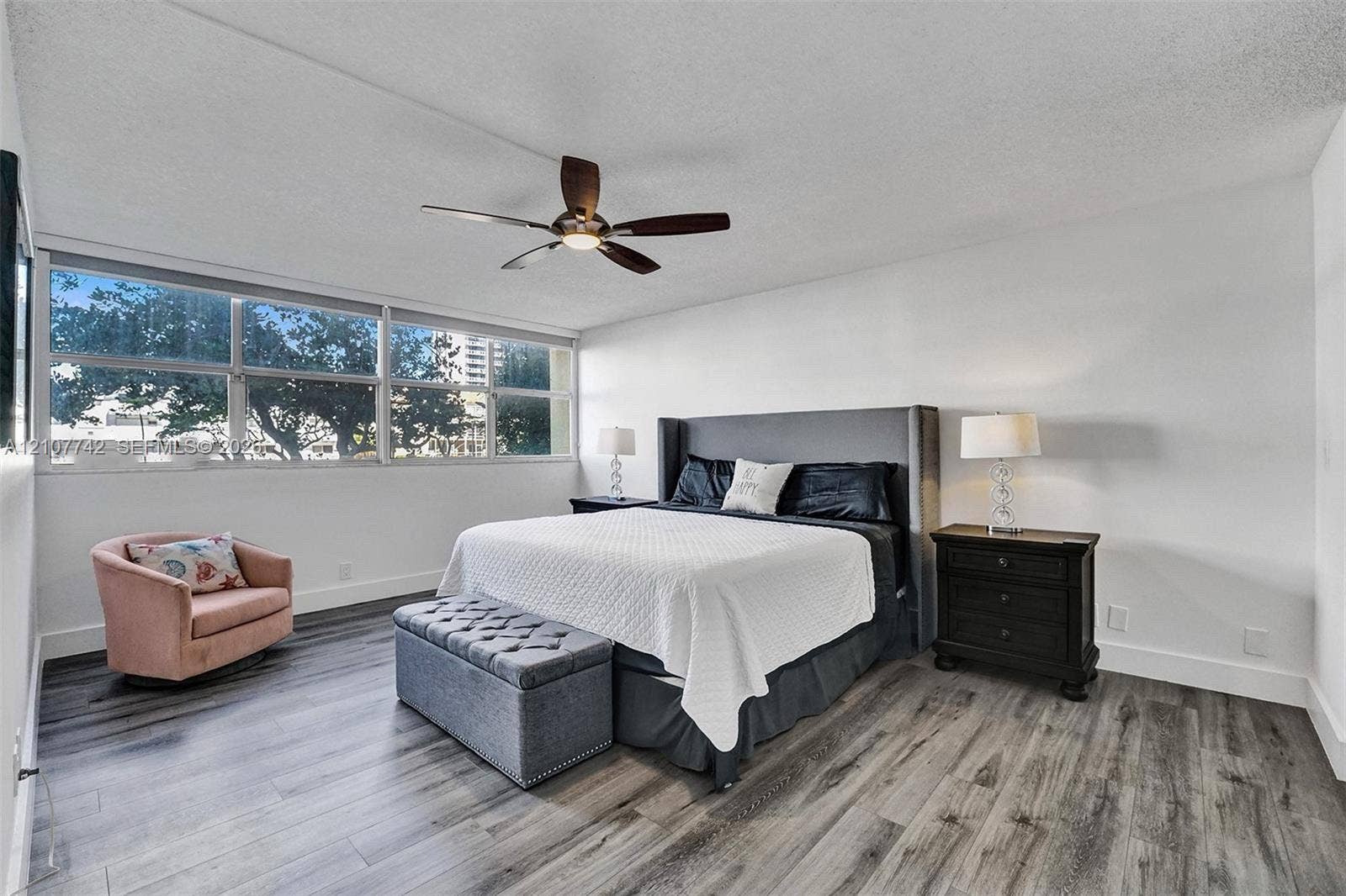 100 Golden Isles Drive, #112, Hallandale Beach, Hallandale Beach, FL 33009 Wood-finish flooring, expansive window pane configuration, and a centrally mounted ceiling fan with integrated lighting
