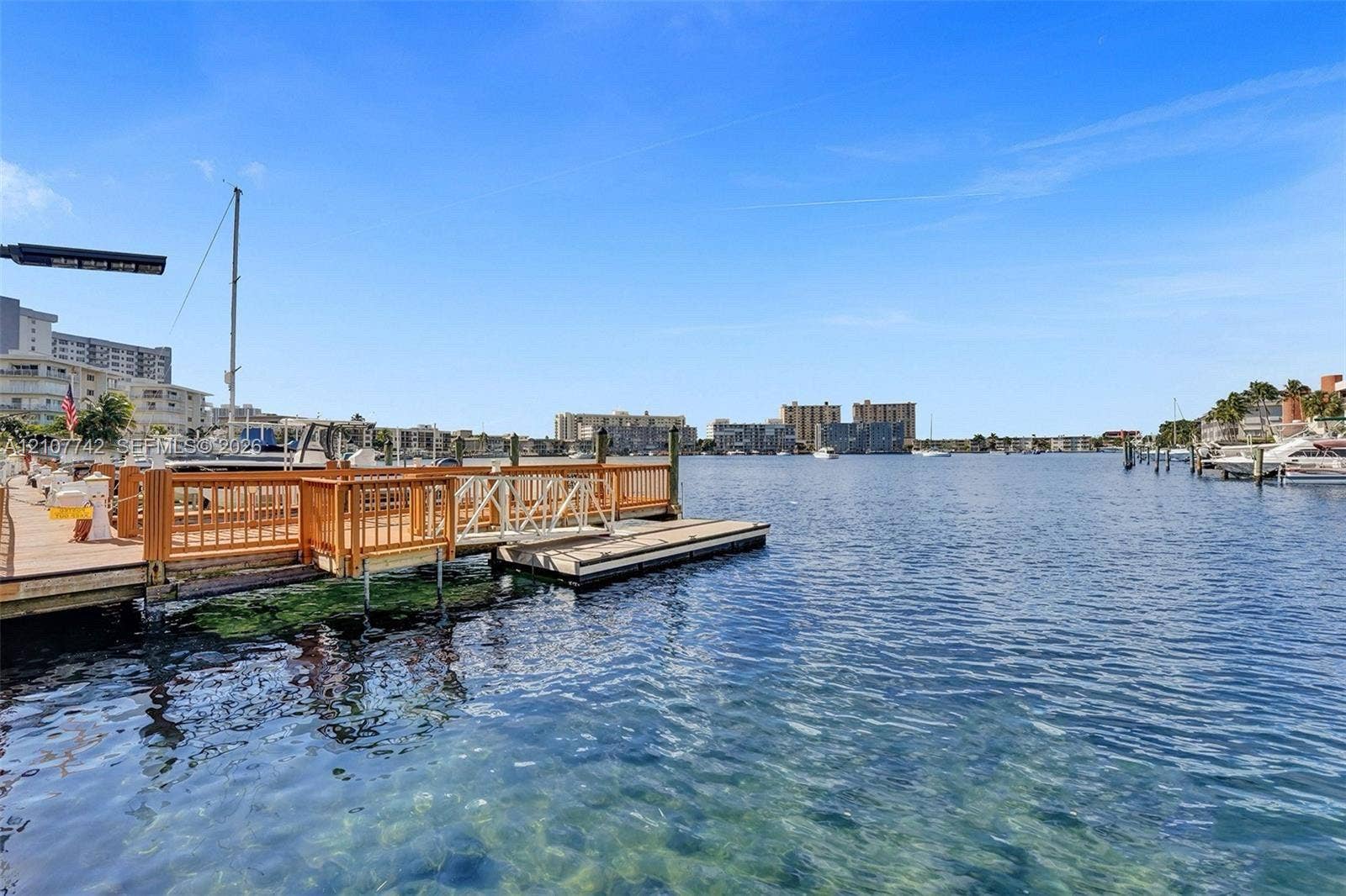 100 Golden Isles Drive, #112, Hallandale Beach, Hallandale Beach, FL 33009 Waterfront bulkhead with a wooden dock featuring a ramp and integrated pilings