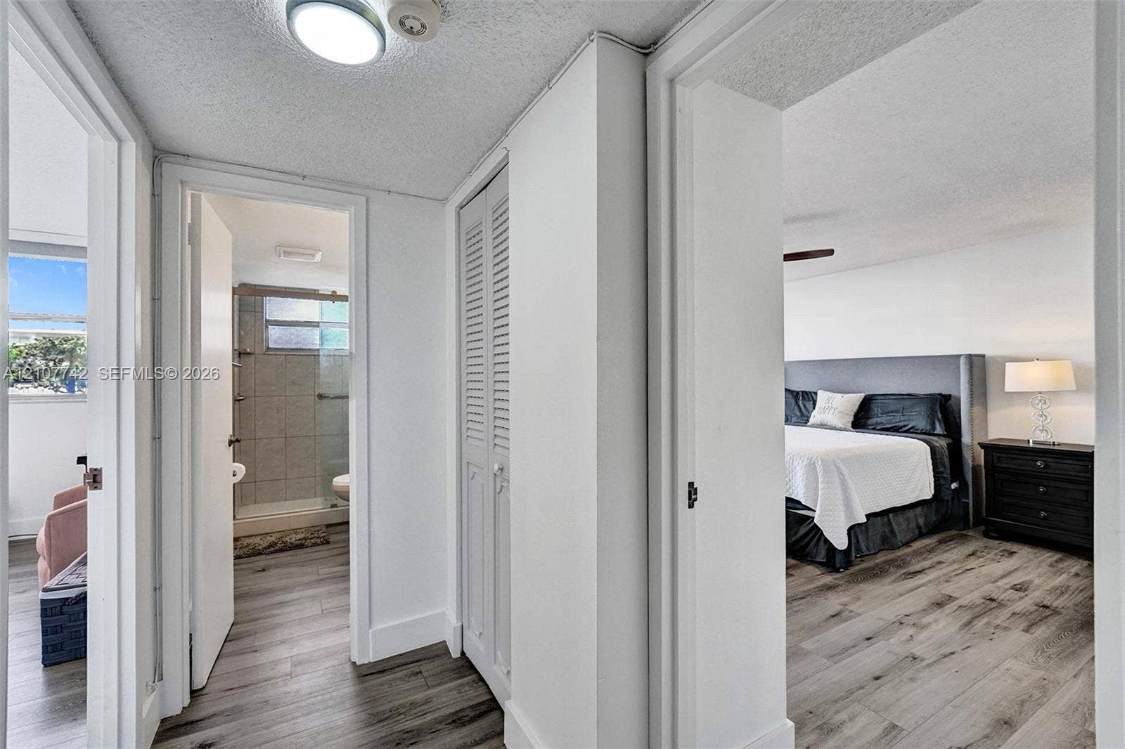100 Golden Isles Drive, #112, Hallandale Beach, Hallandale Beach, FL 33009 Interior hall featuring wood-finish flooring, ceiling-mounted lighting, and louvered bifold closet doors