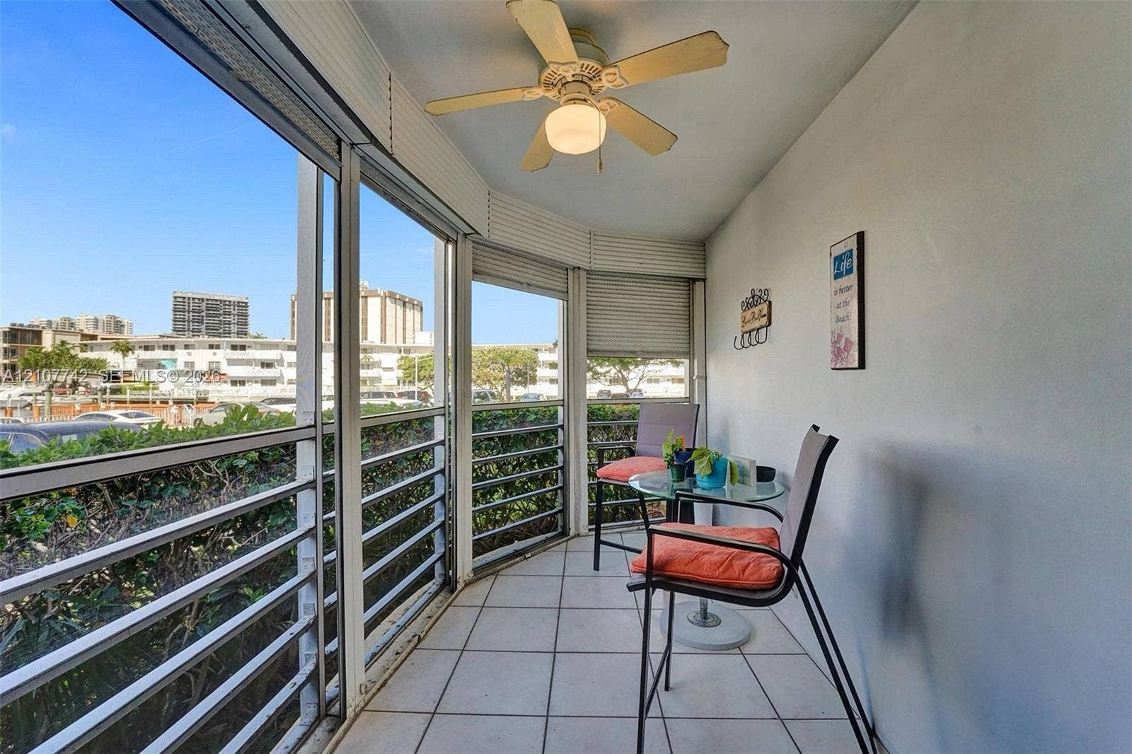 100 Golden Isles Drive, #112, Hallandale Beach, Hallandale Beach, FL 33009 Enclosed balcony featuring tile flooring, ceiling fan, and floor-to-ceiling windows with horizontal blinds
