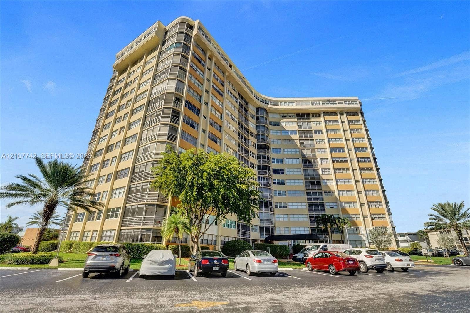 100 Golden Isles Drive, #112, Hallandale Beach, Hallandale Beach, FL 33009 High-rise residential building featuring a curved architectural design, concrete facade, and private screened balconies