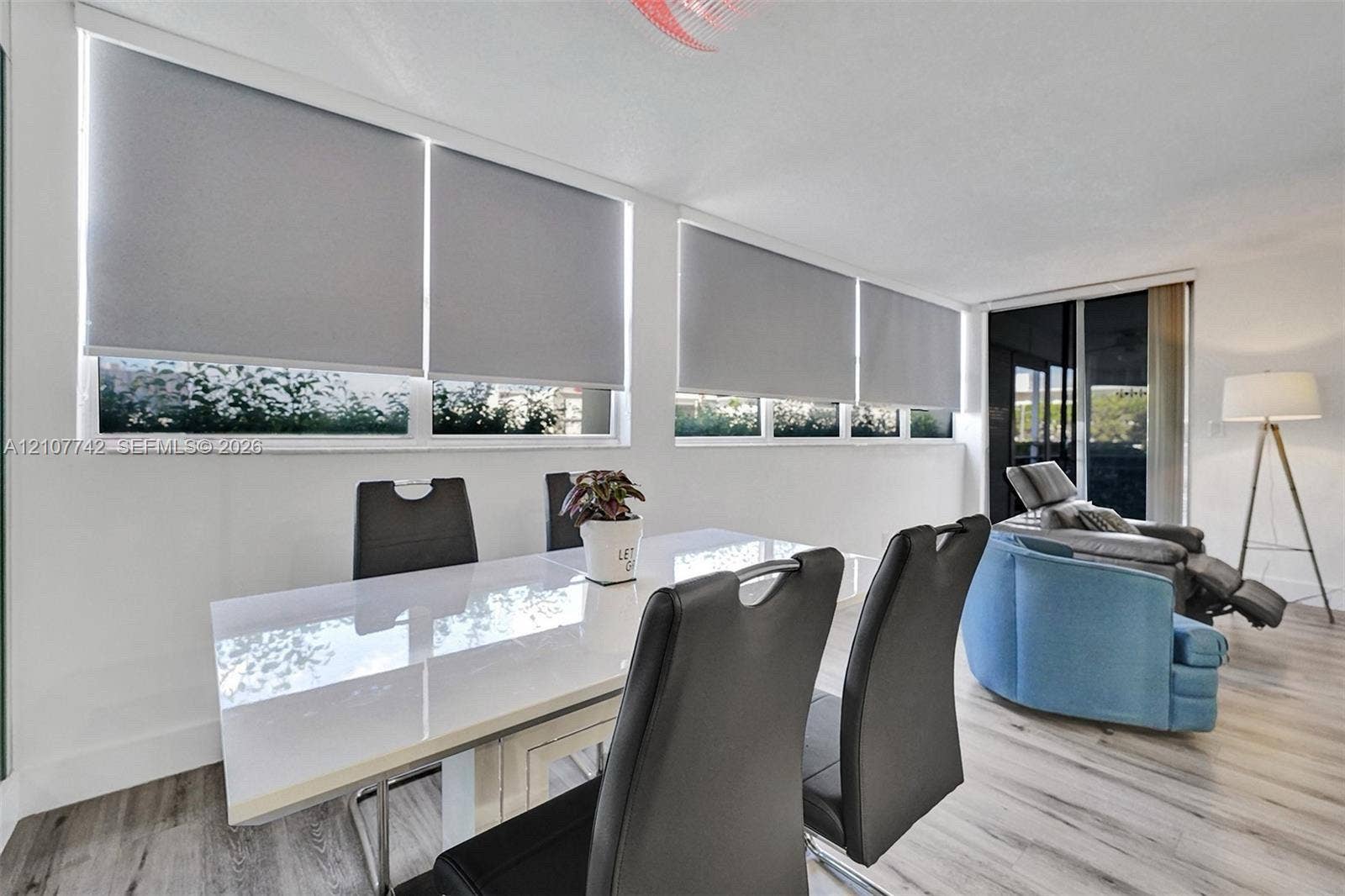 100 Golden Isles Drive, #112, Hallandale Beach, Hallandale Beach, FL 33009 Sun-filled interior featuring expansive picture windows, custom roller shades, sliding glass door, and wood-finish flooring