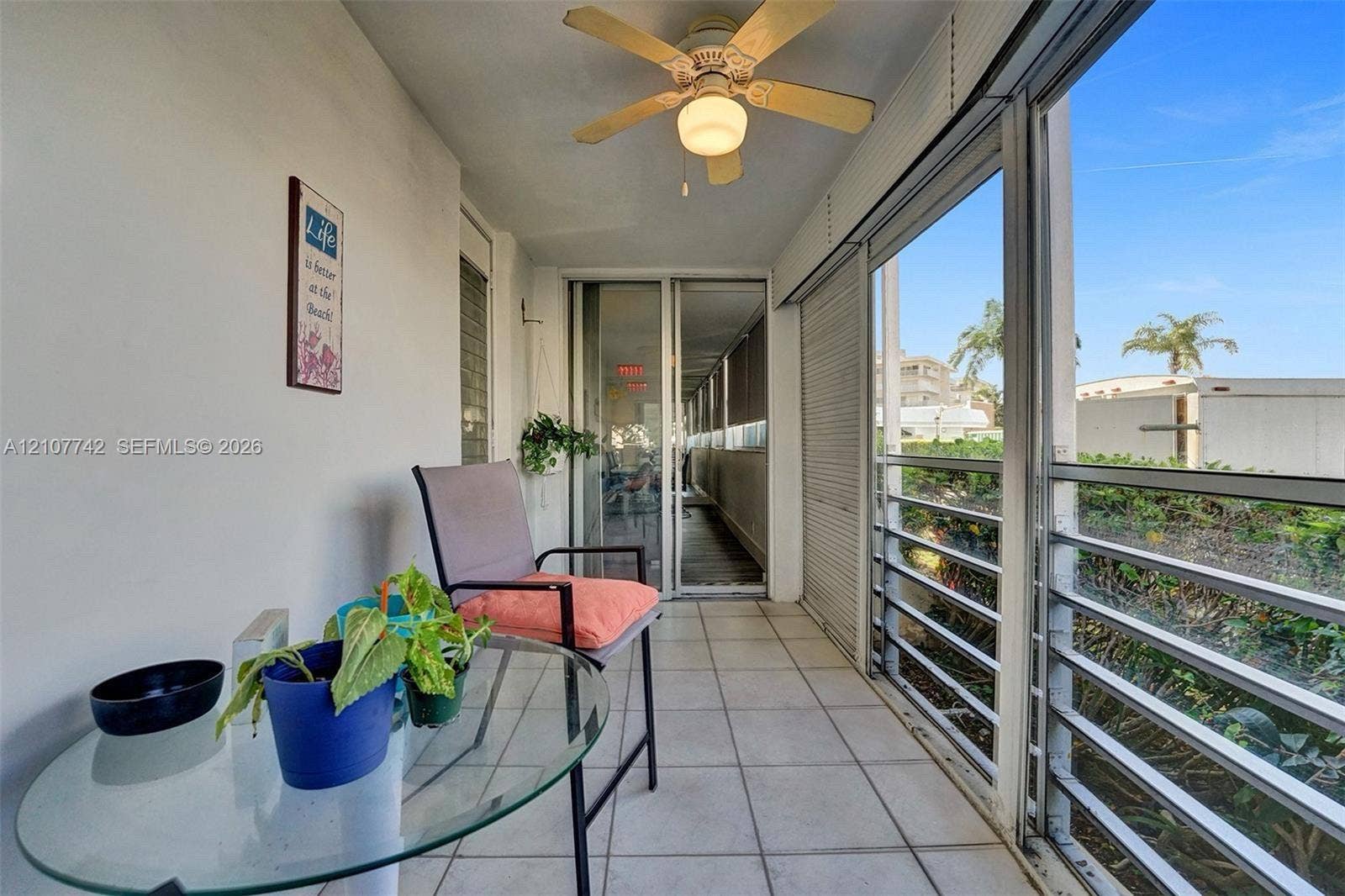 100 Golden Isles Drive, #112, Hallandale Beach, Hallandale Beach, FL 33009 Enclosed lanai featuring large-format tile flooring, a mounted ceiling fan, metal-framed windows, and sliding glass entry doors