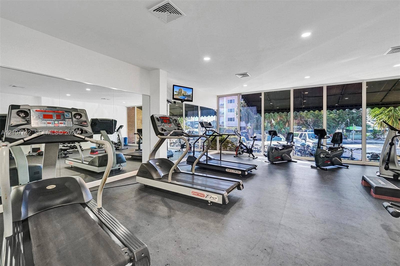 100 Golden Isles Drive, #112, Hallandale Beach, Hallandale Beach, FL 33009 Fitness center featuring wall-to-wall mirrors, floor-to-ceiling glass windows, and durable rubberized flooring