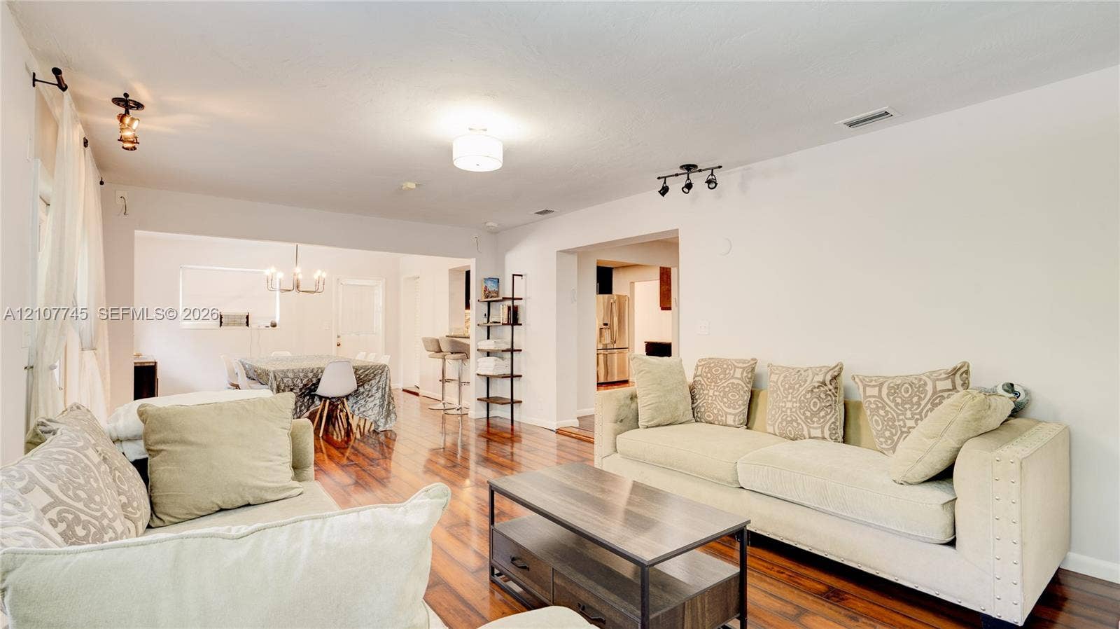 Open floor plan featuring wood-finish flooring, multi-directional ceiling-mounted lighting, and neutral wall tones
