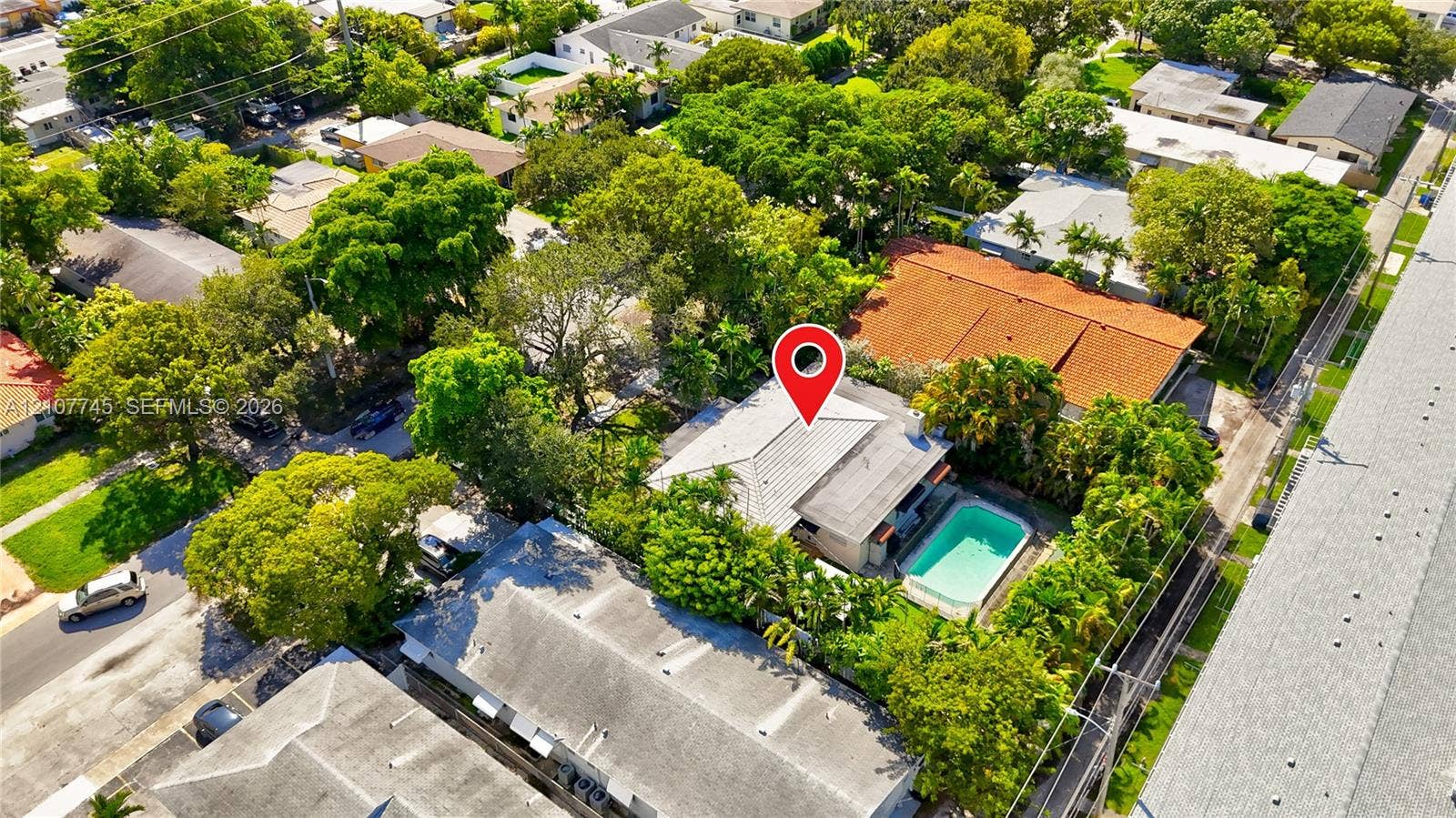 Aerial perspective featuring a tile roof, an in-ground swimming pool, and mature trees within the lot boundaries