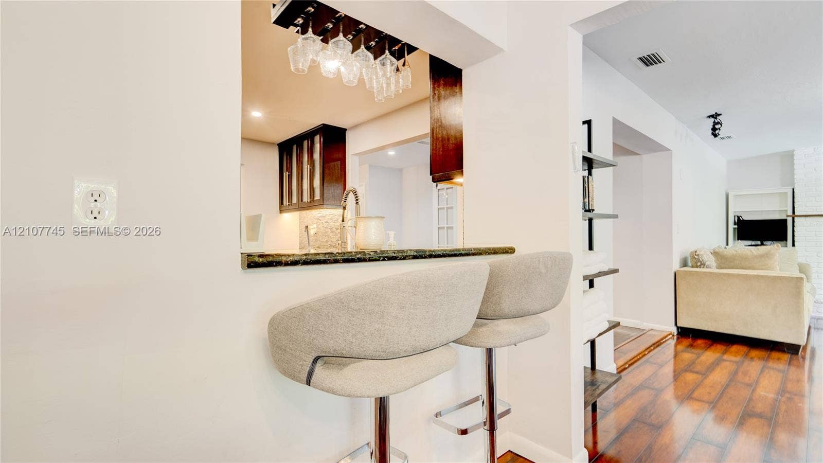 Pass-through window featuring a stone-finish countertop, dark wood-finish cabinetry, built-in stemware rack, and wood-finish flooring