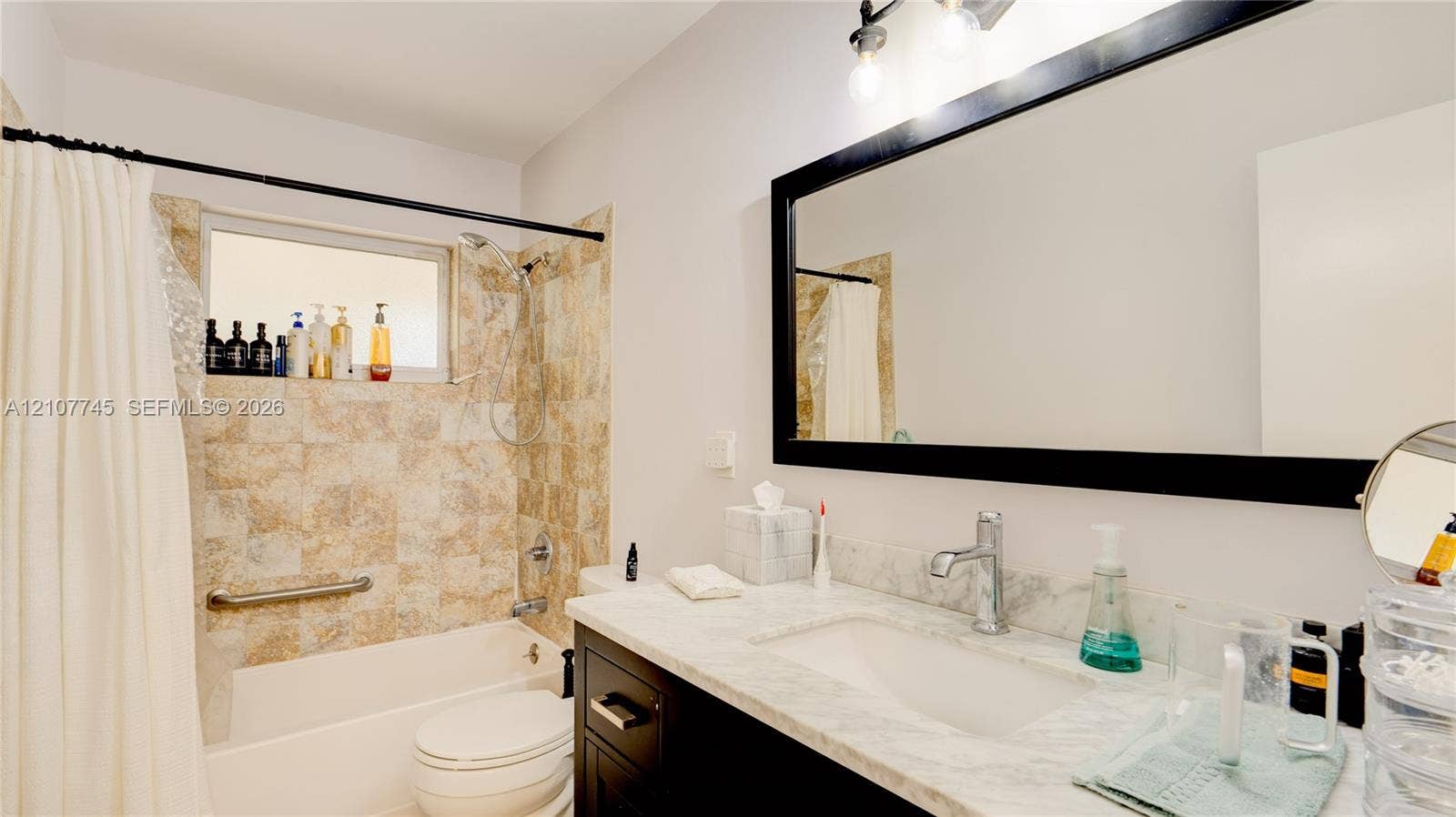 Bathroom featuring a vanity with a light-toned stone countertop, integrated sink, and dark cabinetry