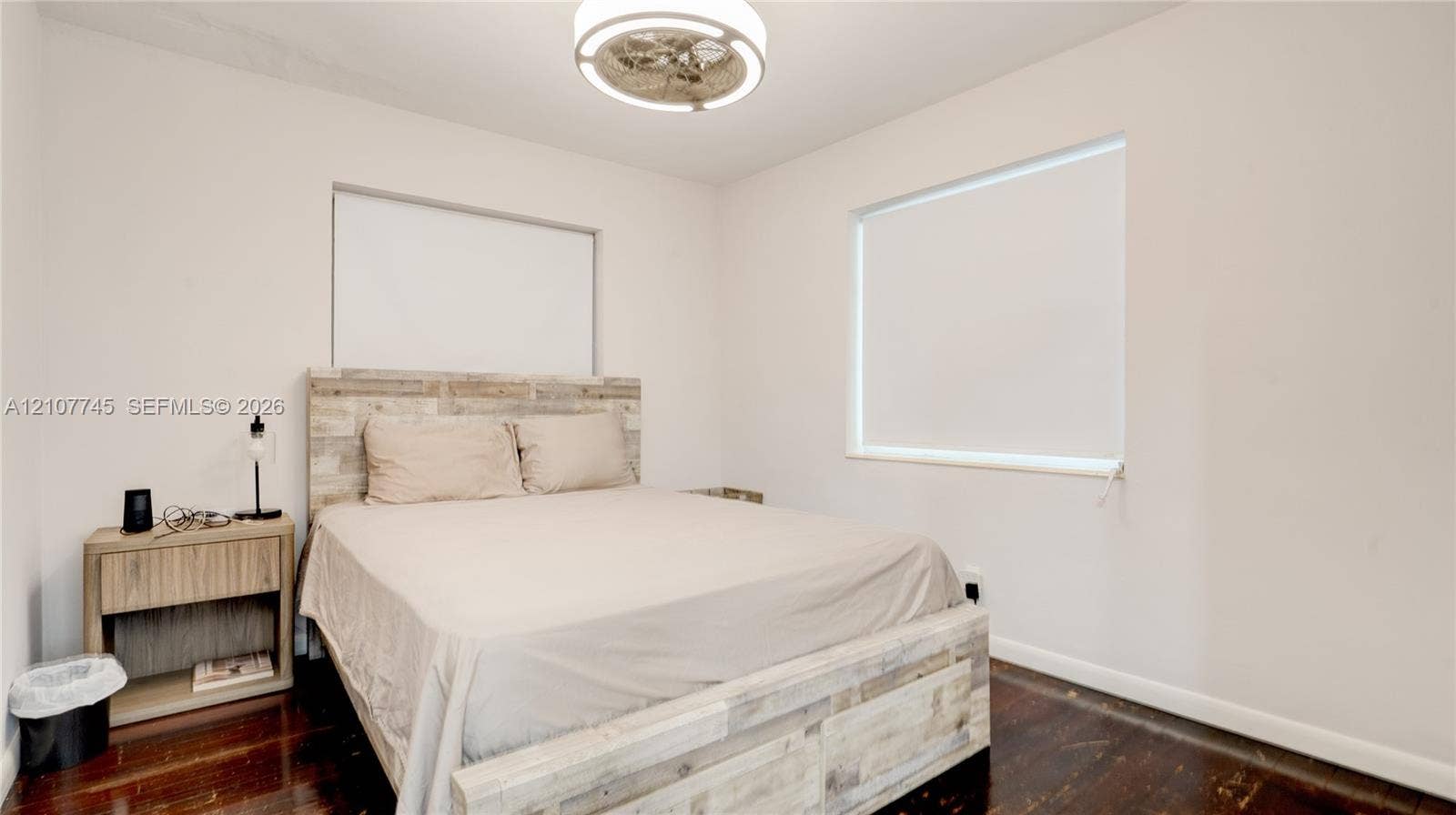 Wood-finish flooring, neutral wall tones, and a modern circular ceiling fan with integrated lighting