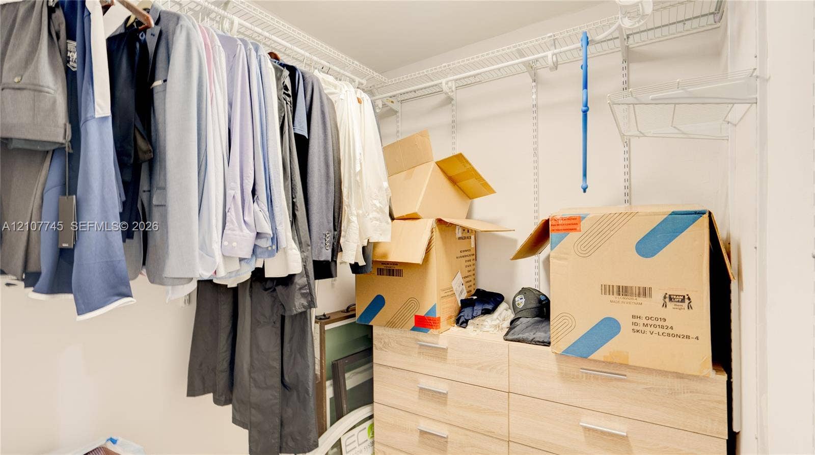 Walk-in closet featuring white wire shelving and built-in light-tone wood-finish drawer cabinetry