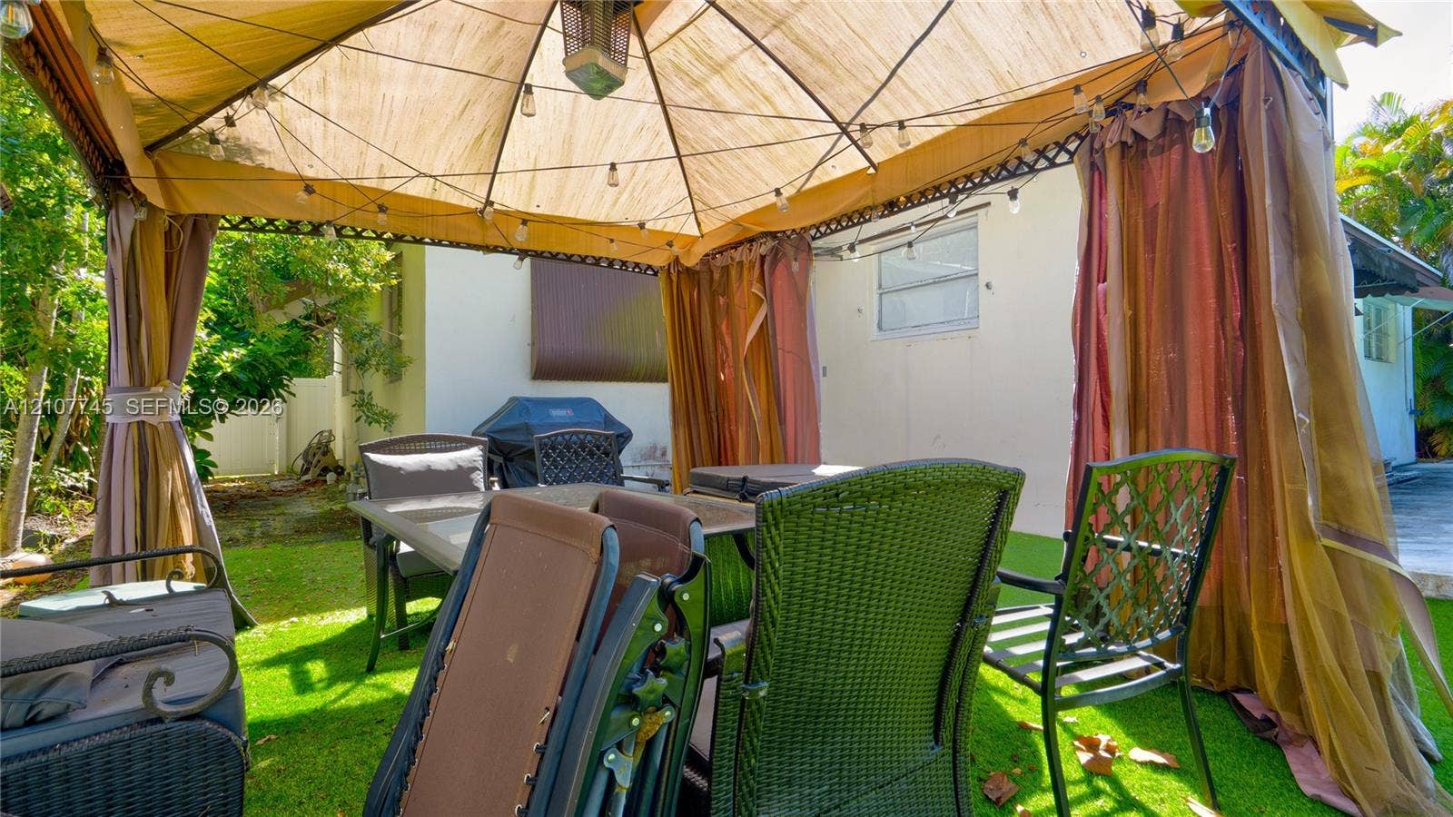 Outdoor living area featuring a covered gazebo, structural metal framework, and synthetic lawn