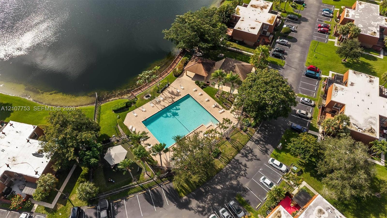 Community pool featuring a concrete deck, covered pavilion, and shoreline proximity