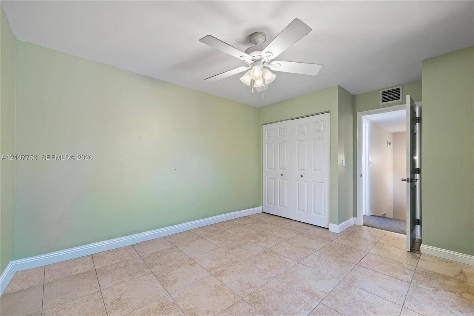 Room featuring tile flooring, a multi-blade ceiling fan with integrated light fixture, and a white double-door closet