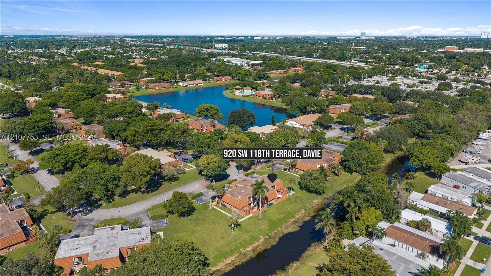 Aerial perspective of property featuring a multi-story exterior, expansive surrounding greenery, and proximity to a large body of water