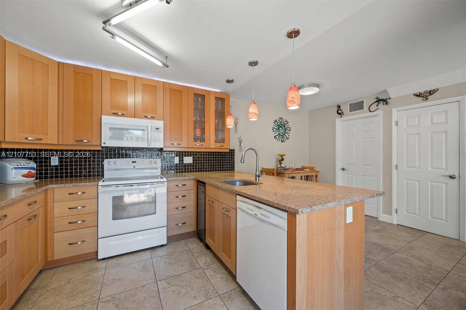 Kitchen featuring light-finish cabinetry, stone-texture countertops, tile flooring, a center island with an integrated dishwasher, and black tile backsplash