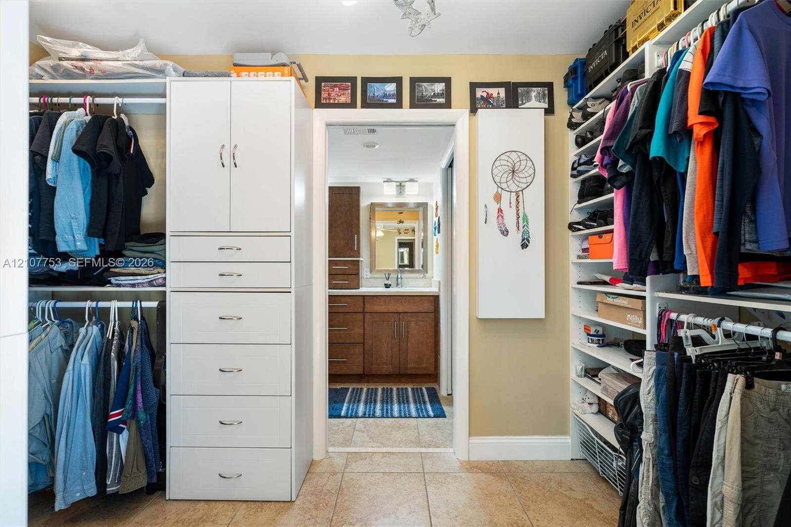 Walk-in closet featuring white custom cabinetry, integrated shelving, and tiled flooring