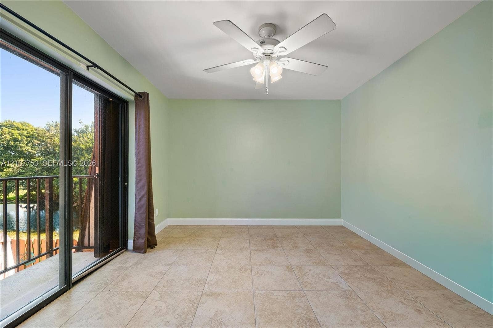 Interior space featuring large-format tile flooring, a central ceiling fan with multi-light fixture, and glass sliding doors opening to a private balcony