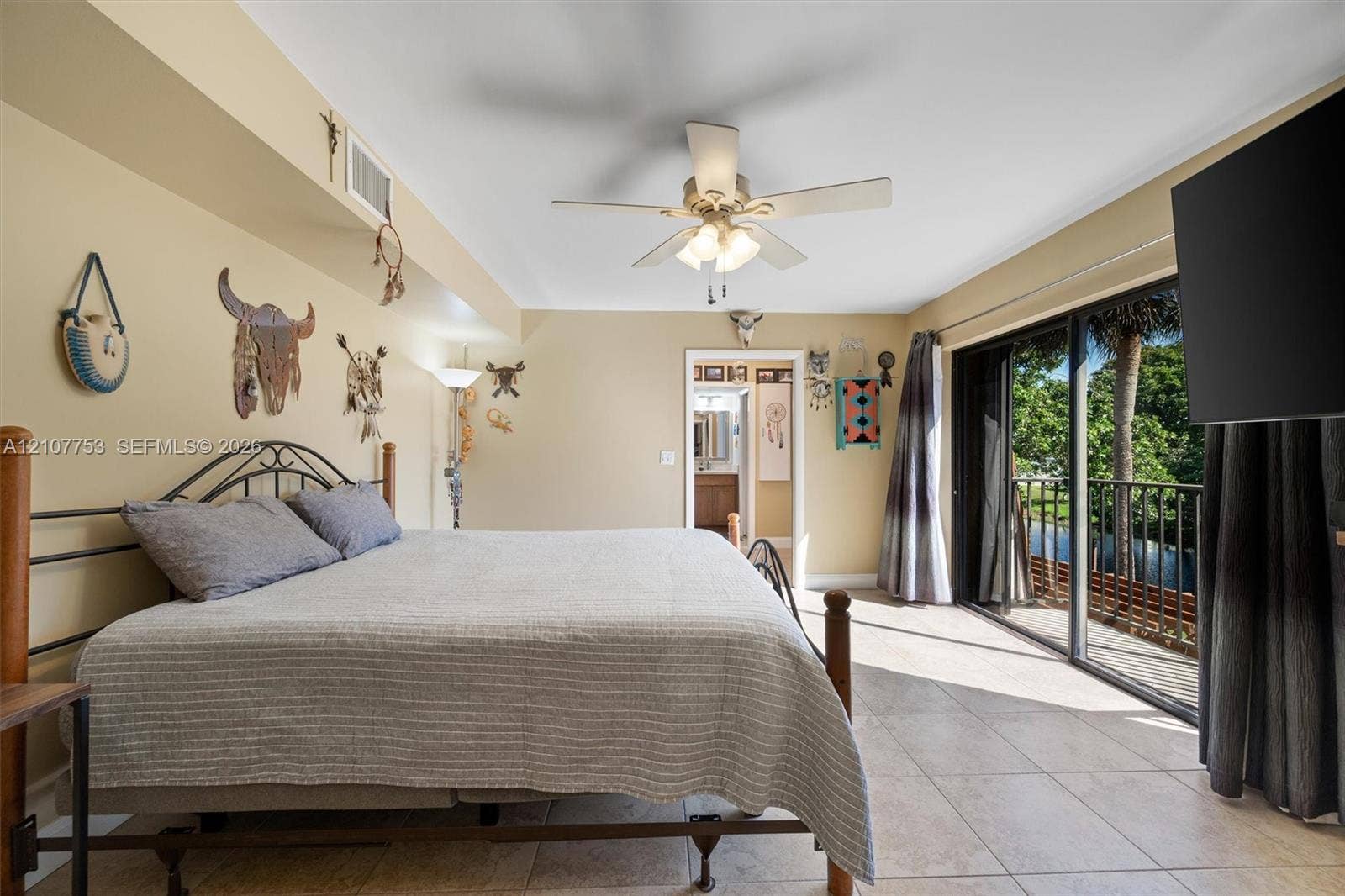 Ceramic tile flooring, ceiling fan with integrated lighting, and expansive sliding glass doors opening to an exterior balcony