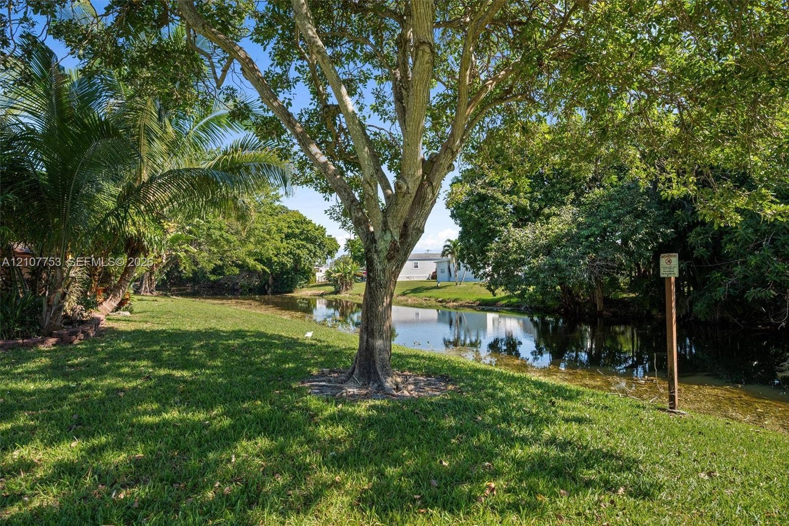 Waterfront lot featuring mature trees, expansive lawn, and lush landscaping