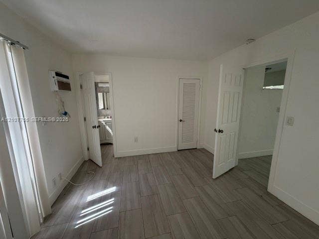 930 SW 29th Street, #A-C, Fort Lauderdale, Fort Lauderdale, FL 33315 Interior space featuring wood-finish tile flooring, white six-panel interior doors, a louvered closet door, and a wall-mounted climate control unit