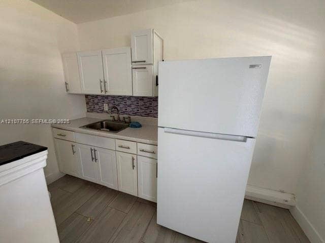 930 SW 29th Street, #A-C, Fort Lauderdale, Fort Lauderdale, FL 33315 Kitchen area featuring white shaker-style cabinetry, solid-surface countertops, mosaic tile backsplash, stainless steel sink, and wood-finish flooring