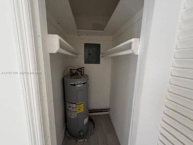 930 SW 29th Street, #A-C, Fort Lauderdale, Fort Lauderdale, FL 33315 Utility closet featuring dual built-in shelving, a water heater, an electrical panel, and wood-finish flooring