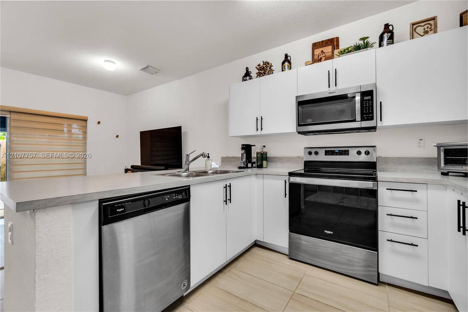 412 NW 12th Avenue, Florida City, FL 33034 Kitchen featuring white cabinetry with matte black hardware, stainless steel appliances, a double-basin sink, and tile flooring