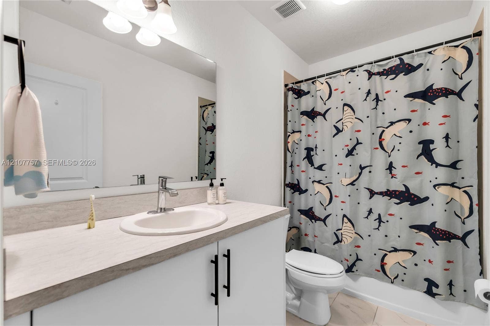 412 NW 12th Avenue, Florida City, FL 33034 Bathroom featuring a vanity with a light-toned countertop, integrated basin, matte black hardware, a wall-to-wall mirror, and overhead track lighting
