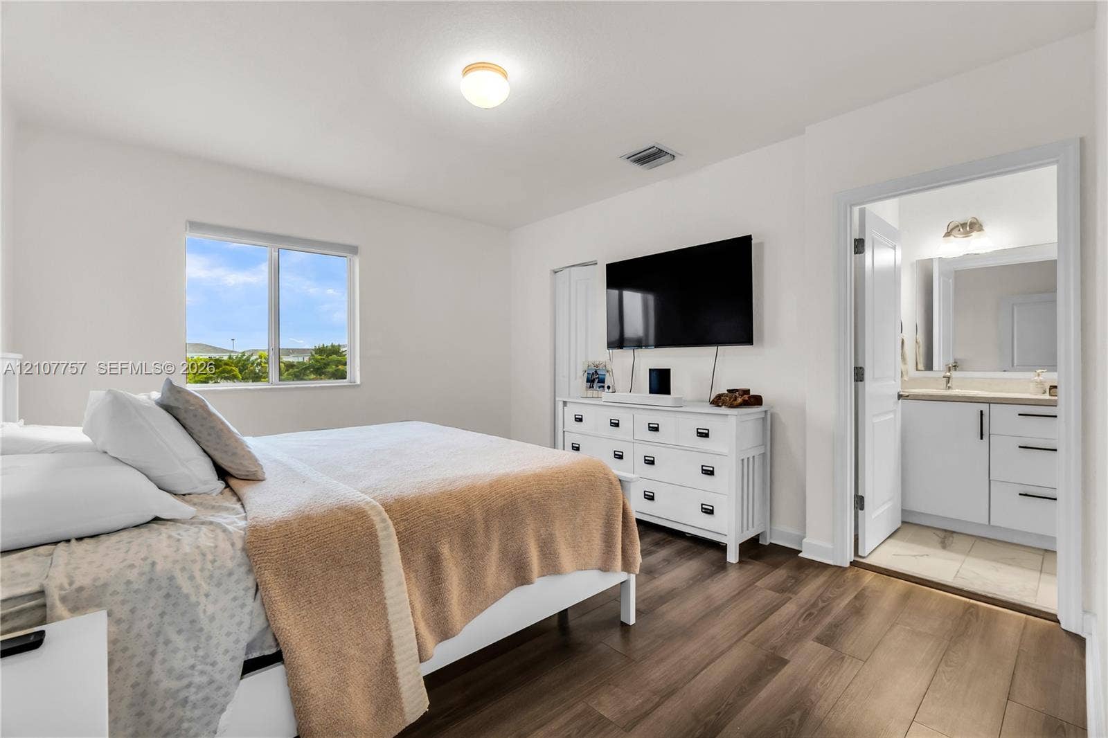 412 NW 12th Avenue, Florida City, FL 33034 Wood-finish flooring, neutral walls, large window with natural light, and an ensuite bathroom featuring a vanity with drawers
