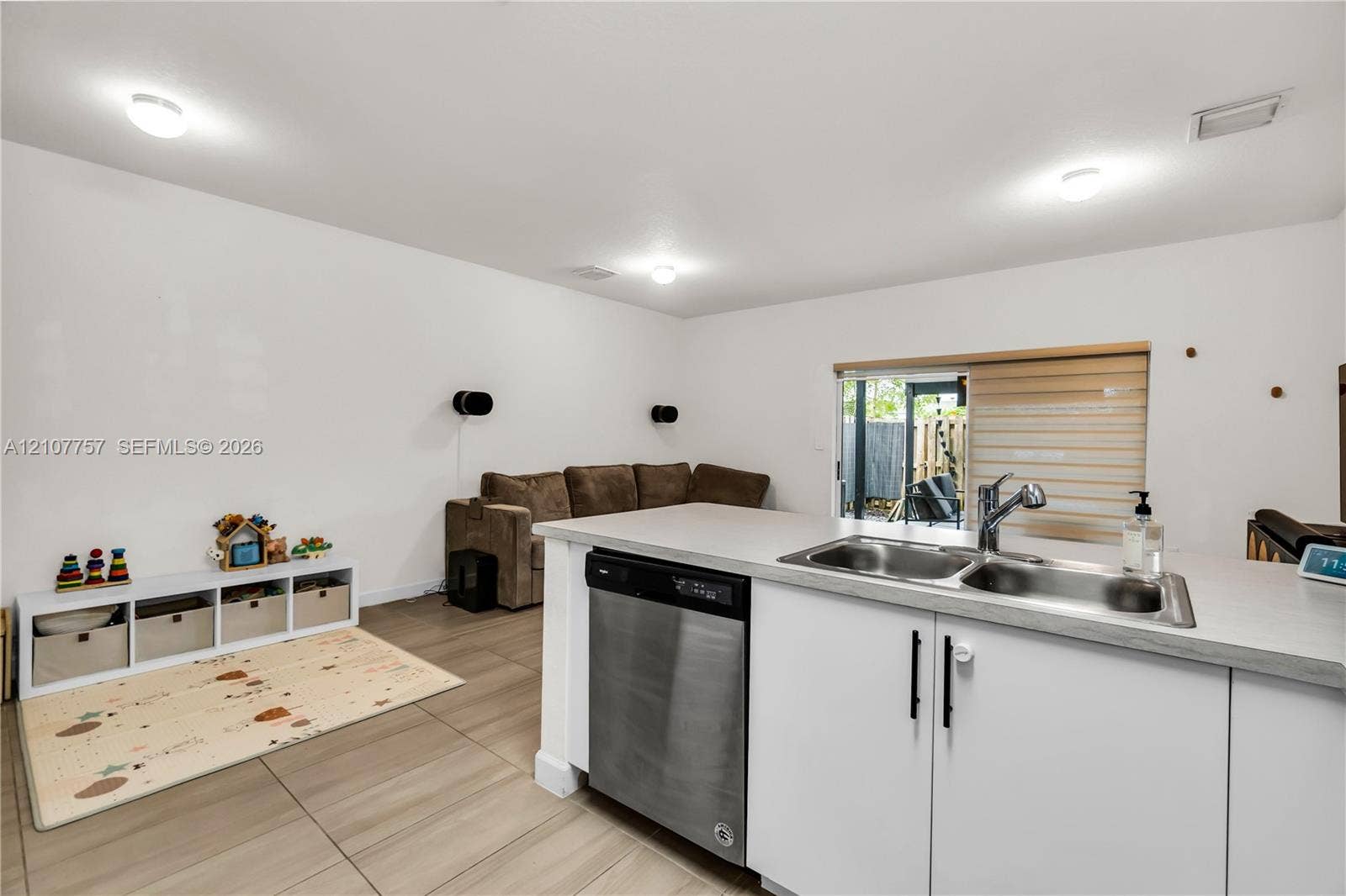 412 NW 12th Avenue, Florida City, FL 33034 Kitchen island featuring a stainless steel dishwasher, dual-basin stainless steel sink with a high-arch faucet, white cabinetry with matte black hardware, and wood-finish tile flooring