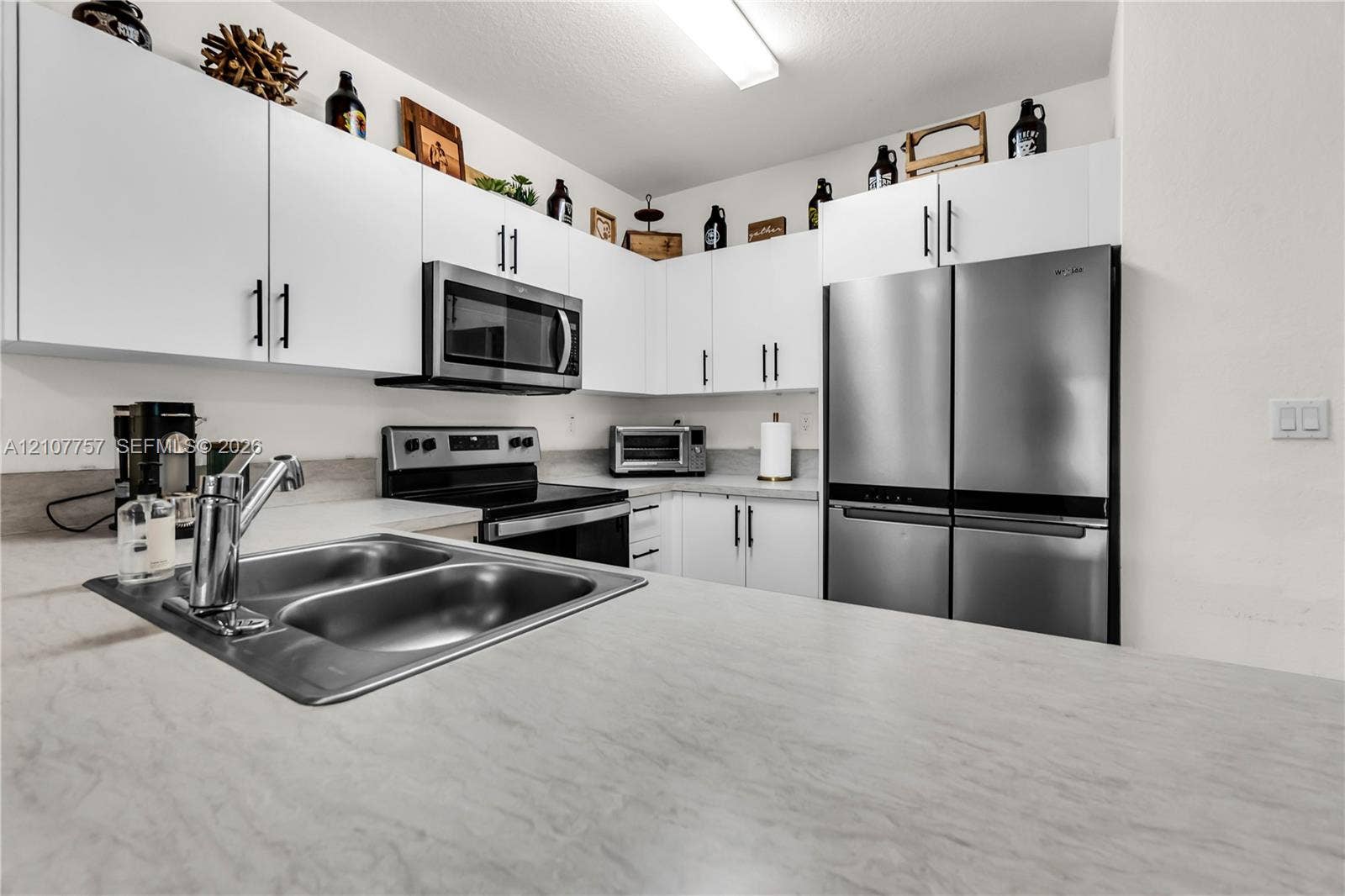 412 NW 12th Avenue, Florida City, FL 33034 Kitchen featuring white flat-panel cabinetry, stainless steel appliances, dual-basin sink with a chrome faucet, and stone-finish countertops