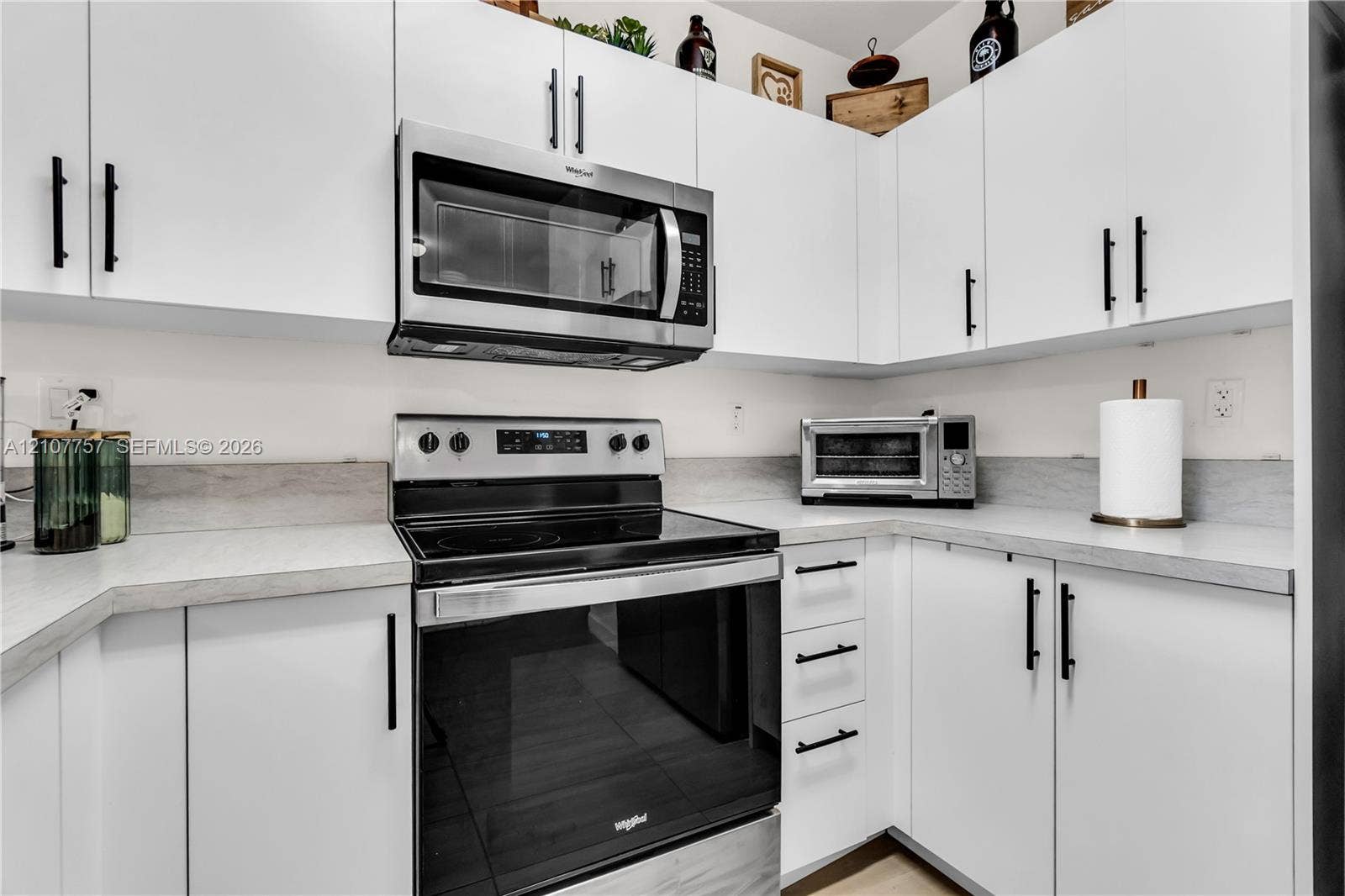 412 NW 12th Avenue, Florida City, FL 33034 White shaker-style cabinetry with matte black hardware, light-toned countertop, and integrated stainless steel microwave and electric range