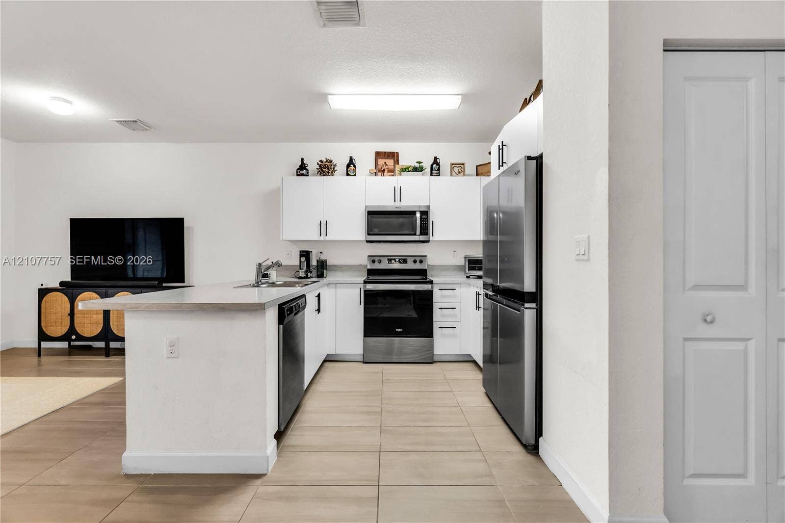 412 NW 12th Avenue, Florida City, FL 33034 Kitchen featuring white cabinetry, stainless steel appliances, a peninsula with a stone countertop, and tile flooring