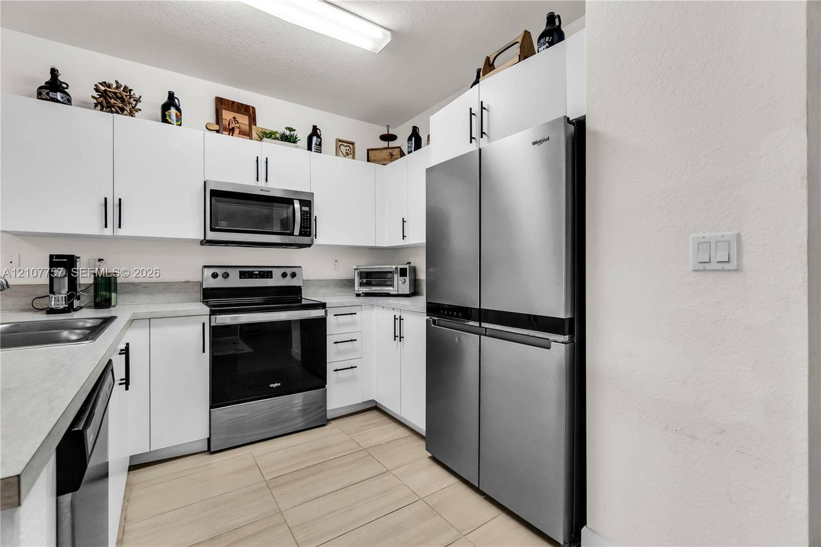 412 NW 12th Avenue, Florida City, FL 33034 Kitchen featuring white flat-panel cabinetry, stainless steel appliances, solid surface countertops, and ceramic tile flooring