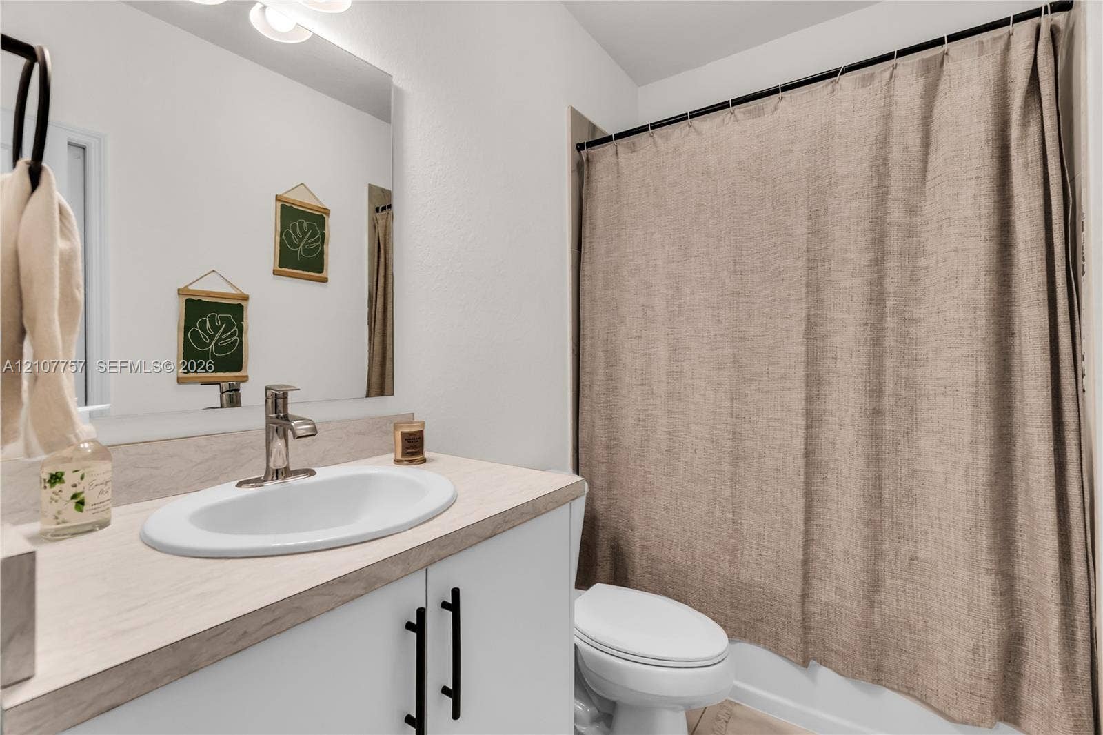 412 NW 12th Avenue, Florida City, FL 33034 Bathroom featuring a vanity with wood-finish countertop, white cabinetry with matte black pulls, integrated oval sink, and a large wall-mounted mirror