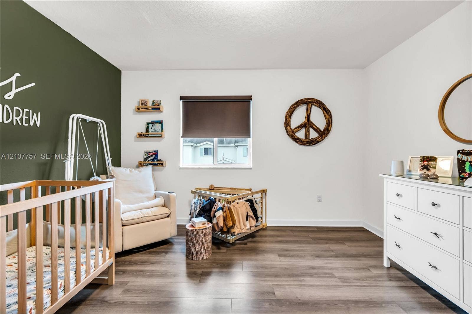 412 NW 12th Avenue, Florida City, FL 33034 Room featuring dark wood-finish flooring, a dark green accent wall, a dual-pane window with a roller shade, and three wall-mounted floating shelves