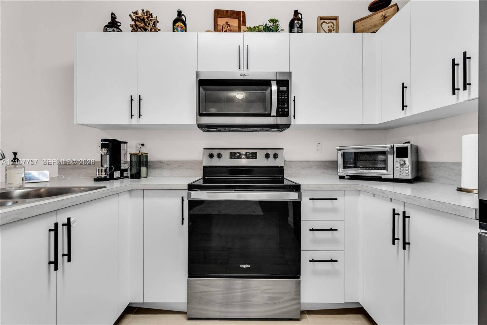 412 NW 12th Avenue, Florida City, FL 33034 Kitchen featuring white flat-panel cabinetry, matte black hardware, stone-finish countertops, and stainless steel appliances