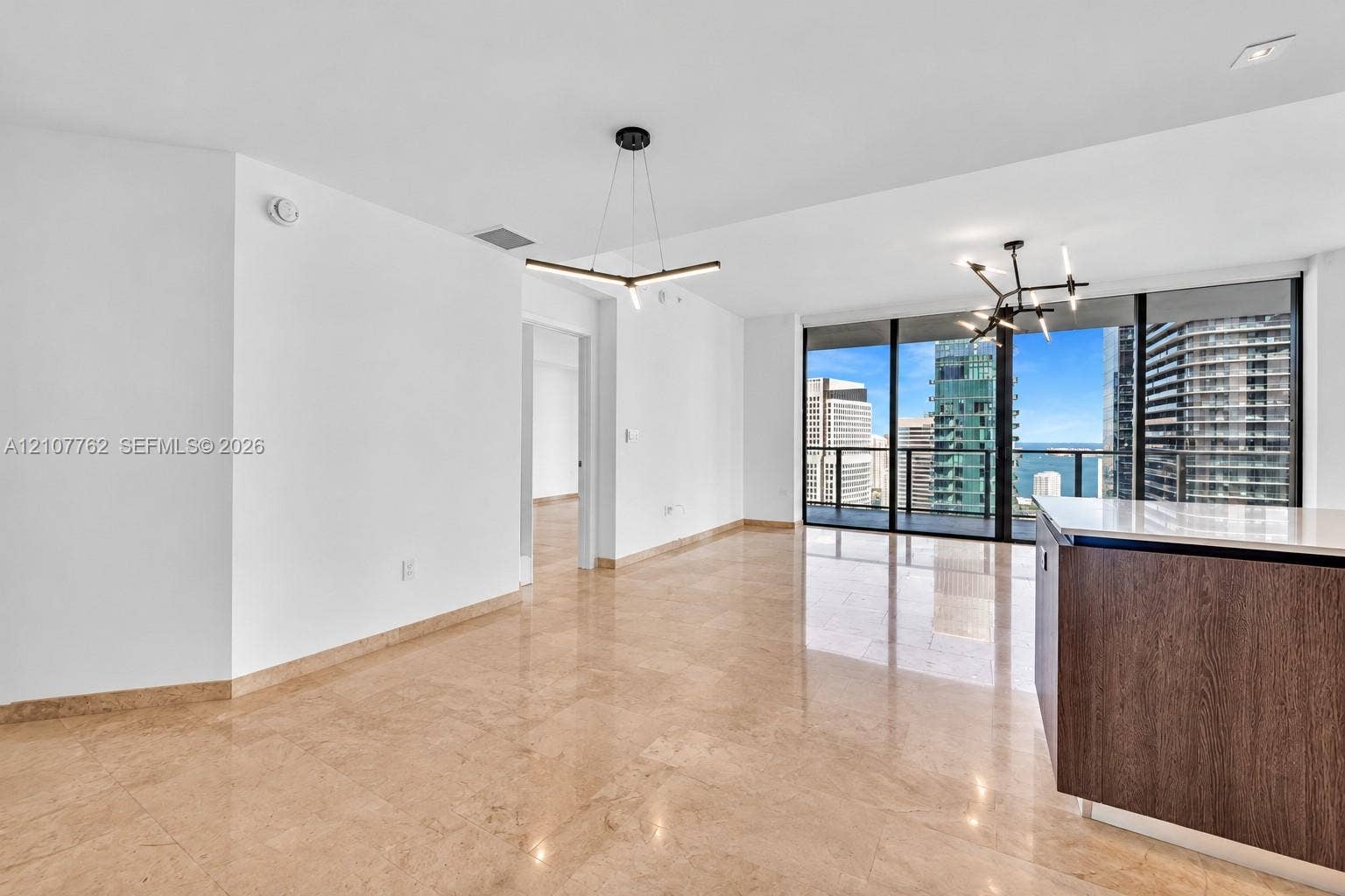 Polished stone flooring, floor-to-ceiling windows, kitchen island with stone countertop, dark wood-finish cabinetry, and contemporary multi-arm light fixtures