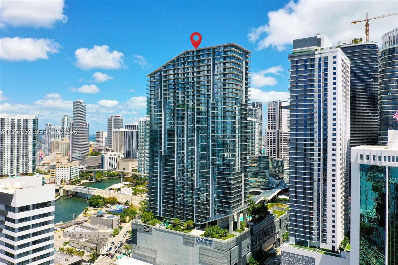 High-rise architectural structure featuring glass-panel exterior walls, tiered balconies, and elevated podium landscaping